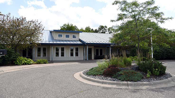 A picture of Three Rivers Dental Clinic, a cozy clinic with trees and native landscaping out front.
