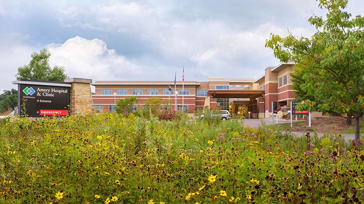 The main entrance of Amery Hospital & Clinic with a garden of wildflowers in the front.