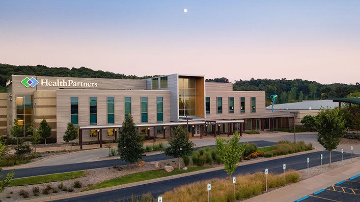 An image of the Hudson Hospital and Clinic entrance surrounded by trees and other native plants. 