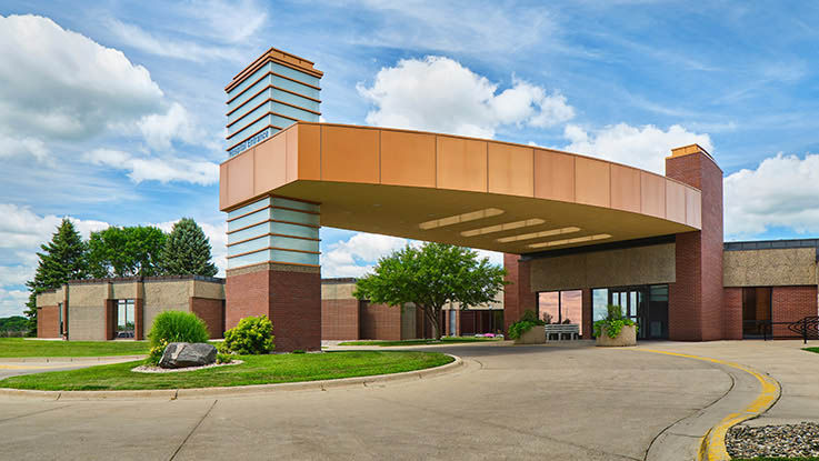 A picture of the entrance of Hutchinson Hospital & Clinic. It has a circular driveway and large port cochere for easy access to the main doors.