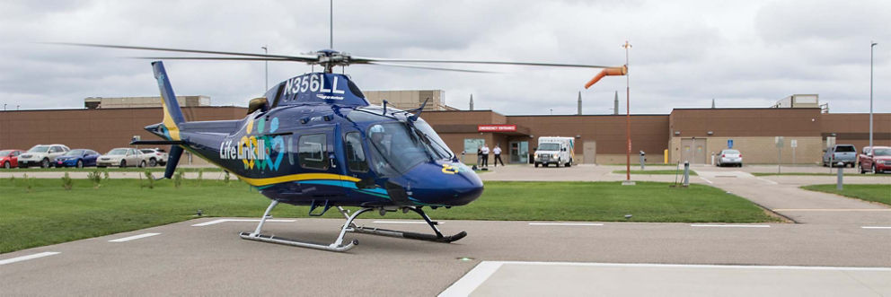 An ambulance helicopter waits in front of the Olivia Hospital Emergency Center entrance, ready to take off.