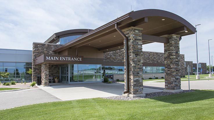 A picture of the entrance of Olivia Hospital & Clinic. It has a wide driveway and large port cochere for easy access to the main doors.