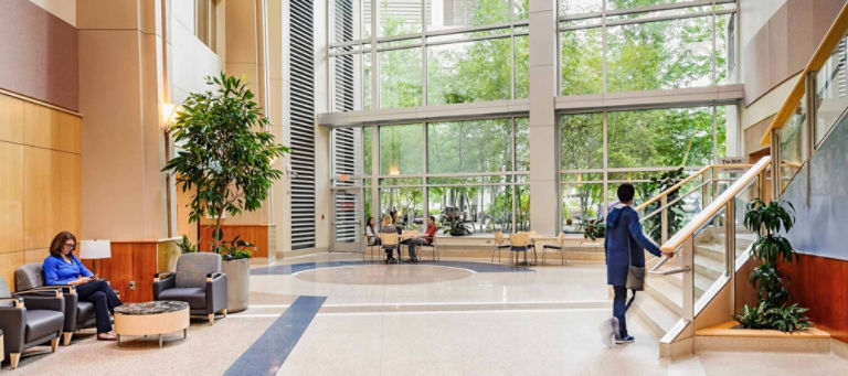 An interior shot of the modern Regions Hospital lobby. People mill about the lobby chatting, reading and walking.