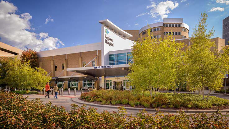 Two patients walk up to the west entrance to Regions Hospital. The west entrance is nestled among park-like landscaping.