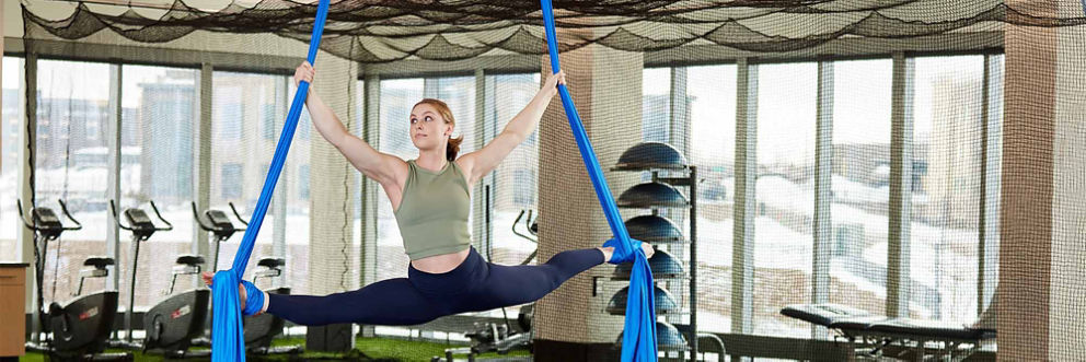 An athlete practices the splits on the silks in the performing arts medicine training gym.