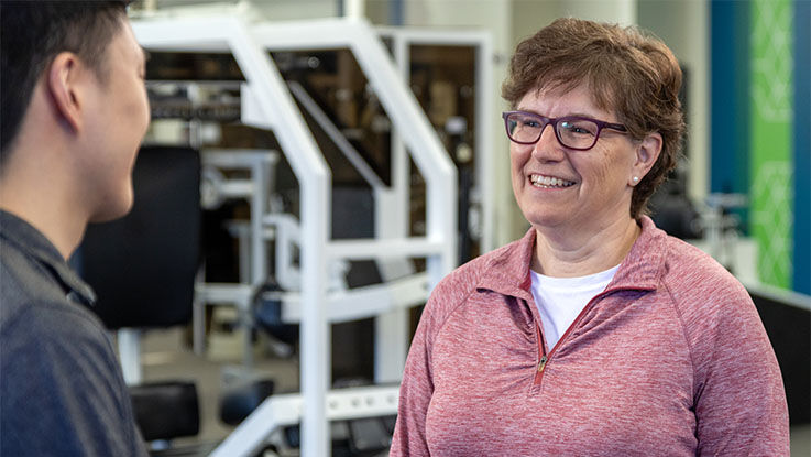 A patient talks with her physical therapist in the TRIA gym.