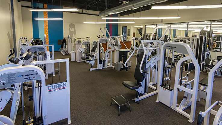 A bright gym full of different types of MedX exercise equipment.