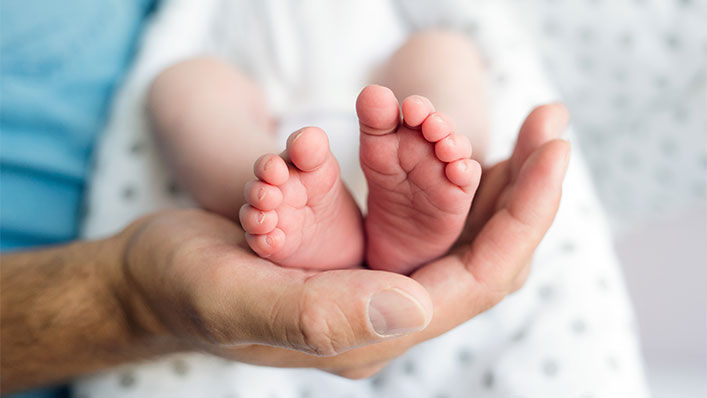 Man holding babies feet in the palm of his hand