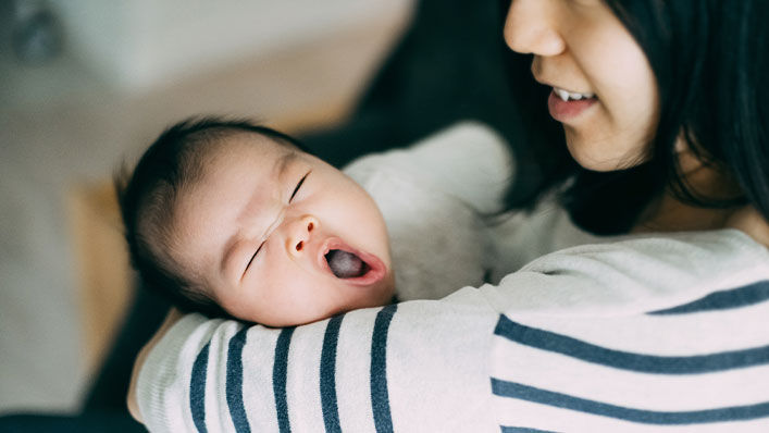 Mother smiling and holding her newborn