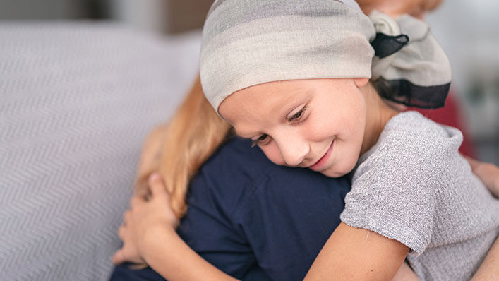 A child recovering from cancer gets a hug from her mom.