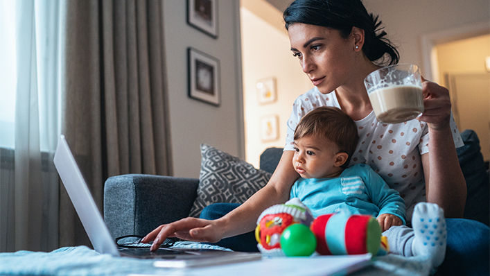 Mother with a baby using laptop at home.