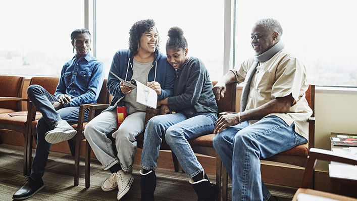 A family laughs together while sitting in a hospital waiting room