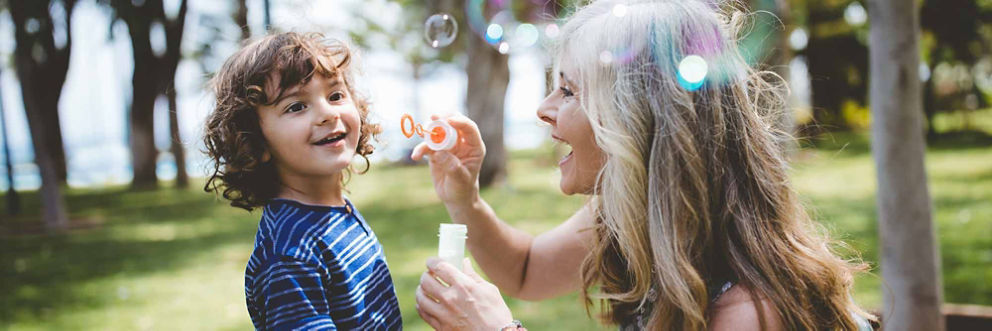 A grandma blows bubbles with her grandson on the shores of a Minnesota lake.