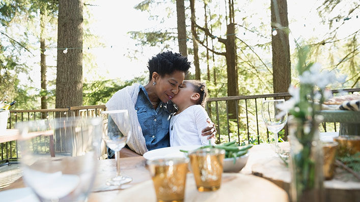 Lady hugging daughter on deck in woods