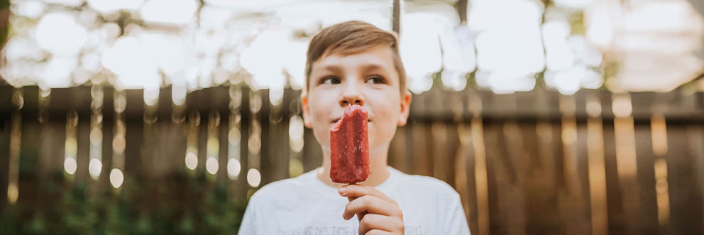 A boy enjoys a popsicle on a warm sunny day.
