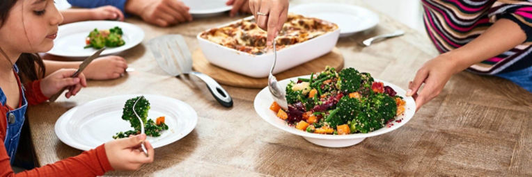 A young man and woman chat and laugh as they lounge in their open tent. 