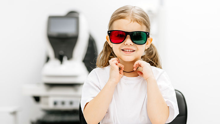 A girl wears specialty red and green glasses as part of her vision therapy.