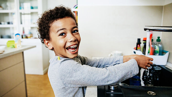 A smiling boy helps cook in the kitchen.