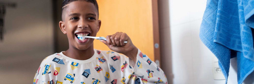 A boy brushes his teeth.