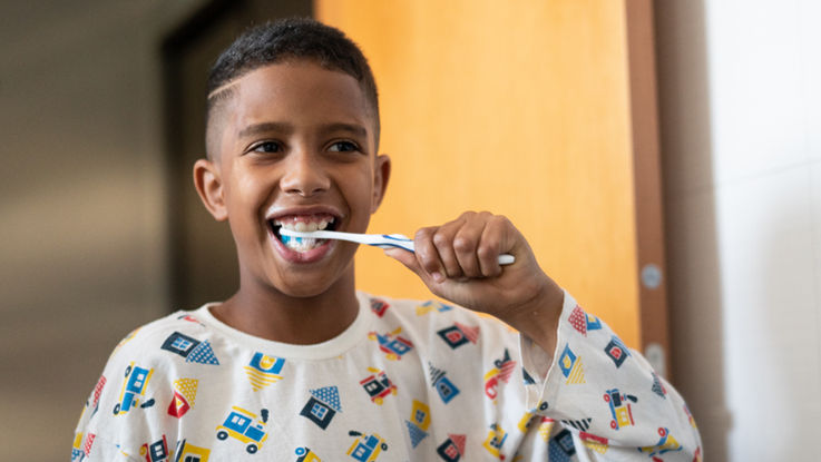 A young boy brushes his teeth in a bathroom.