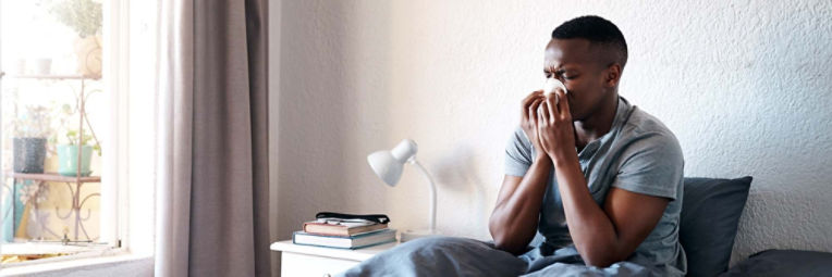 Woman on the couch wrapped in a cozy blanket sipping a mug of tea.
