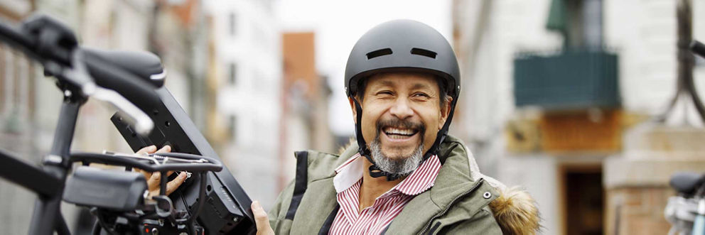 A man wearing a helmet smiles as he gets ready to ride a bicycle