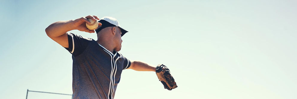 A baseball player pulls his arm back in mid-throw.