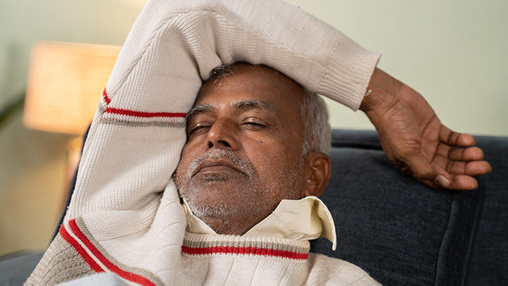A man takes a short snooze while sitting on a couch.