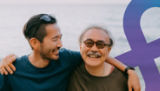 Father and son smile with the ocean in the background.