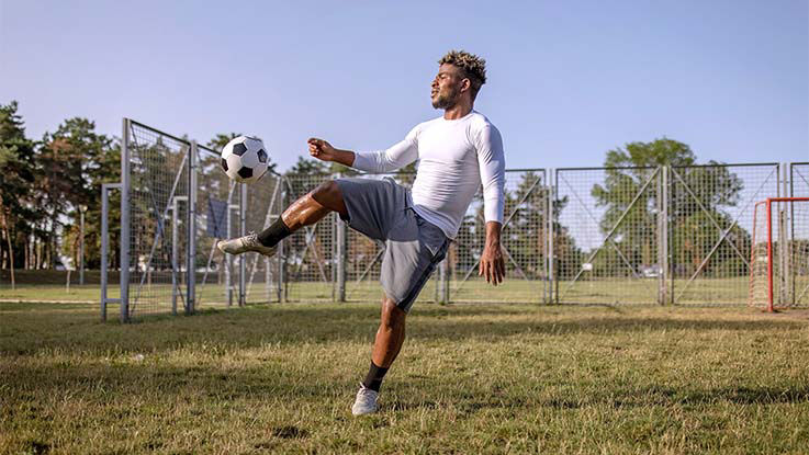 A soccer player makes a very large kick while twisting slightly in the abdomen.