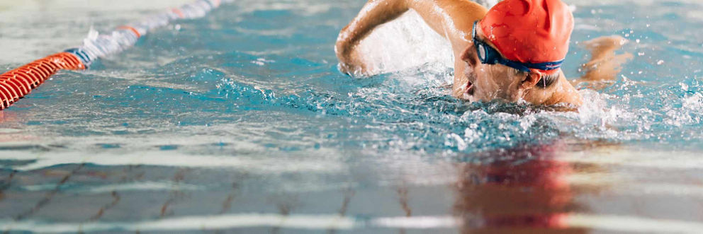 A swimmer takes a breath mid-stroke in a pool.