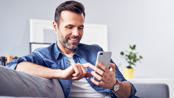 A man accesses resources on his mobile phone as he sits at home