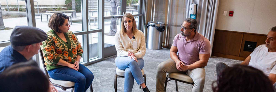 A woman shares her experiences during a group therapy session while others listen attentively