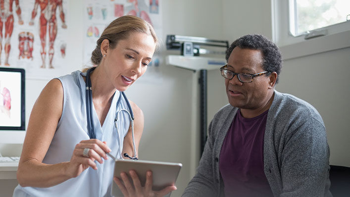 A woman doctor showing a male patient results on an ipad.