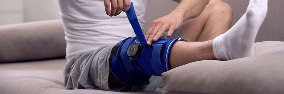 A man tightens the straps on his knee brace.