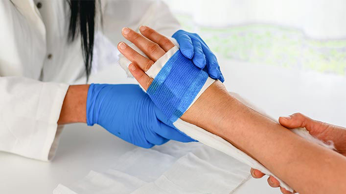 Close up of nurse bandaging up a patient's hand.