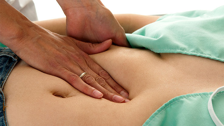 A doctor gently presses against a person’s upper abdomen to diagnose an epigastric hernia. 