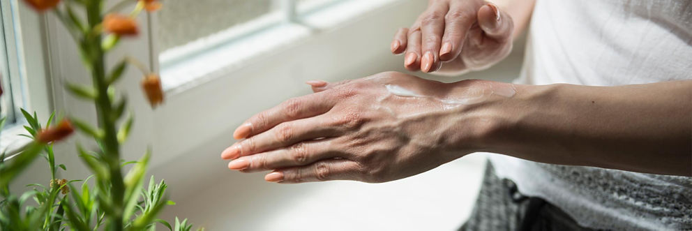 A woman rubs lotion into her hands.