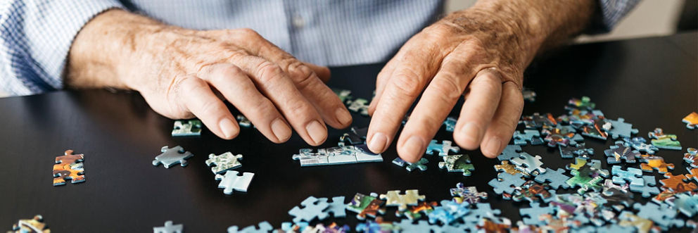 An older man fits puzzle pieces together.