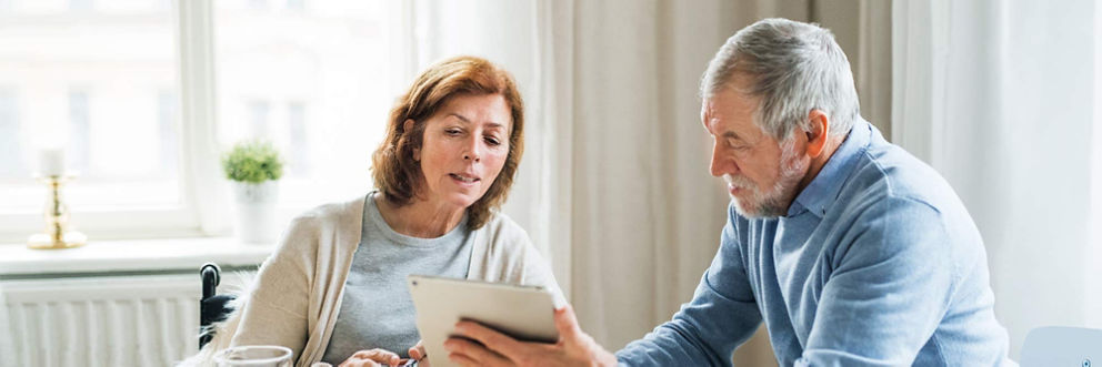 An older couple looks at information on a tablet.