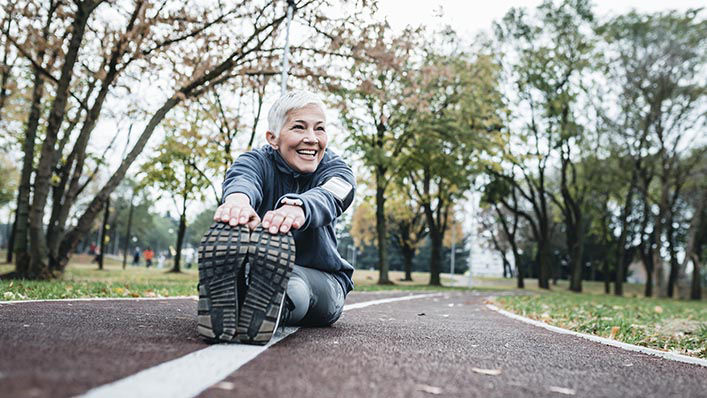 An older woman stretches outdoors before beginning a run