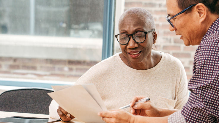 An older man reviews paperwork with a smiling older woman.