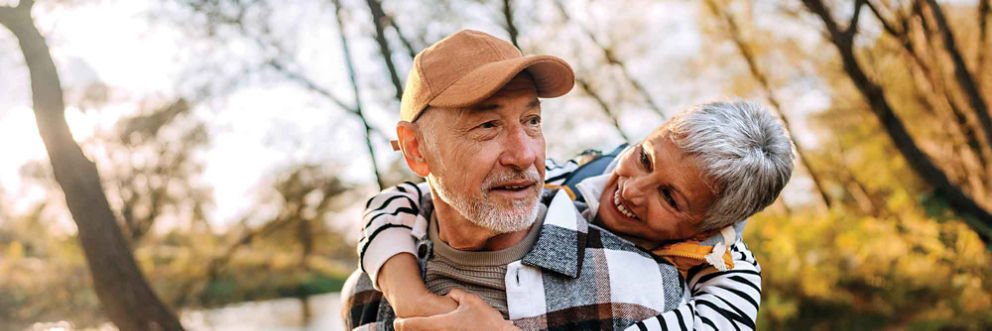 Walking in the woods together, an older husband and his wife enjoy the scenery