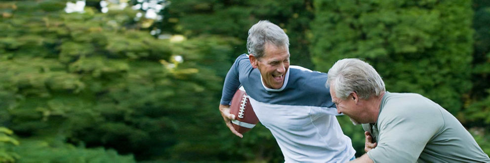 Two older men laugh during a pickup game of football.
