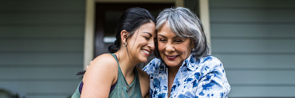 Senior woman and adult daughter laughing on porch