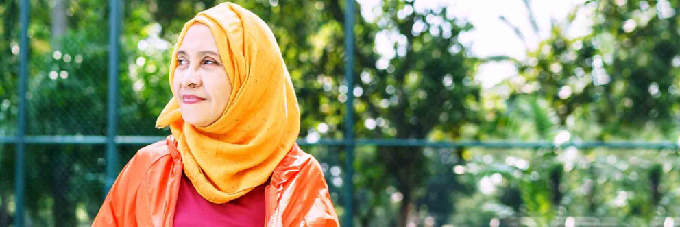 A woman wearing a headscarf stares thoughtfully into the distance.