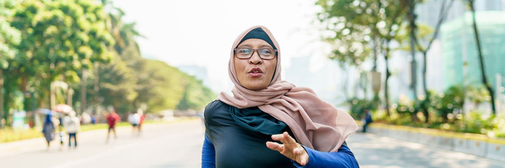 A woman wearing a headscarf goes for a run in the park.