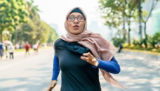 A woman wearing a headscarf goes for a run in the park.