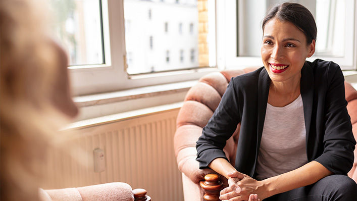 A smiling therapist listens attentively to a patient during a session.