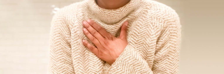 A person wearing a sweater has their hand placed over their heart